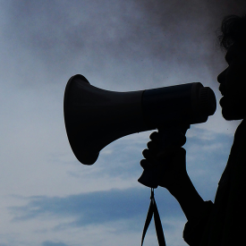 Image of a person in silhouette speaking through a megaphone
